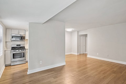 A spacious room with wooden flooring and white walls.